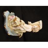 A German porcelain figural candlestick in the form of a cherub riding a dolphin,