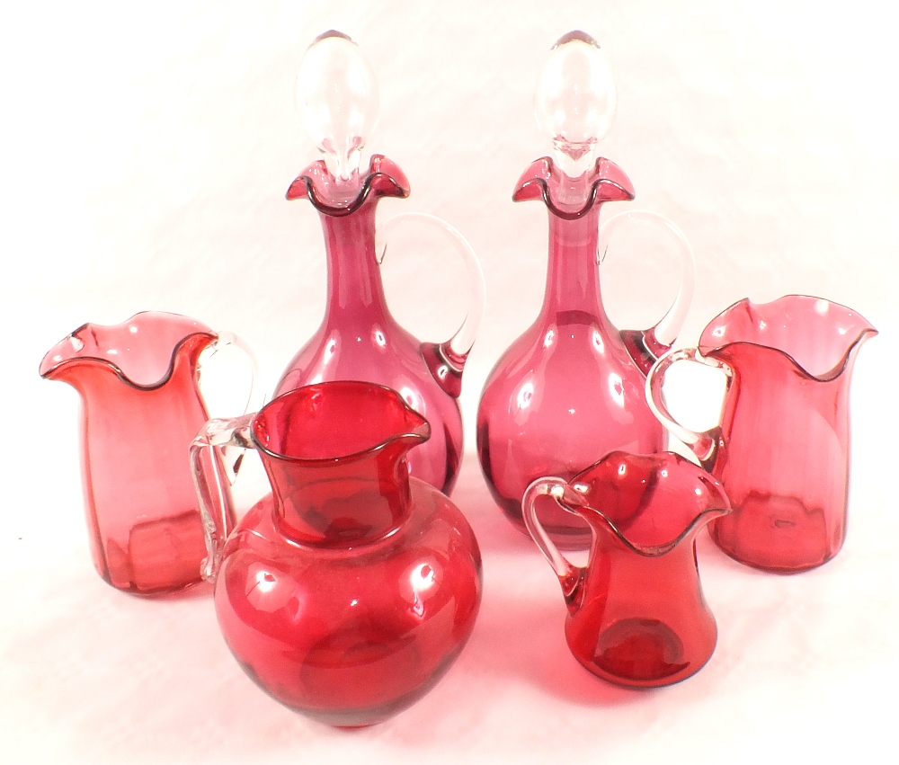 A pair of Cranberry claret jugs and four various jugs