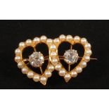 A Gold brooch of double heart form set with Pearls and a large Diamond set within each heart