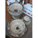 Two weathered circular concrete garden urns on column bases