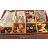 A wooden box containing a large quantity of various fly making accessories including feathers,