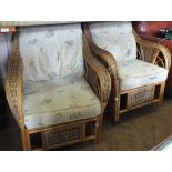 A pair of cane conservatory armchairs and a table