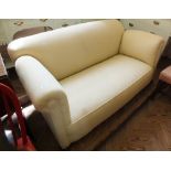 A cream upholstered day bed with drop end
