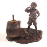 A bronzed figure of a boy next to a barrel,