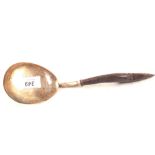 A spoon with large white metal bowl and a carved wooden handle,