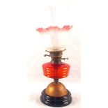 An oil lamp with red glass bowl and pink etched shade