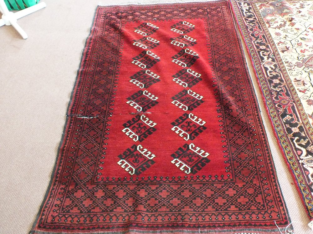 An Afghan red ground rug with repeating central design,