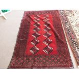 An Afghan red ground rug with repeating central design,