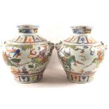 A pair of Chinese polychrome bulbous vases with animal mask handles, mounted warriors and emblems,