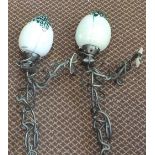 A pair of wrought iron wall lamps with iridescent green glass globes