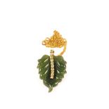 A carved Jade pendant in the form of a leaf mounted in 9ct Gold with a row of Peridots to centre,