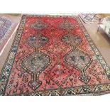 A Persian red ground carpet with joined central medallions,