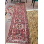 A Persian red ground runner with repeating geometric medallions,