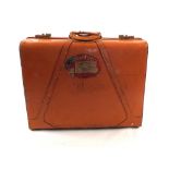 A salmon coloured leather Oshkosh suitcase with Cunard Queen Mary label