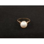 A continental yellow metal ring set with a single Pearl,