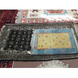 A Persian black ground floral rug and one other
