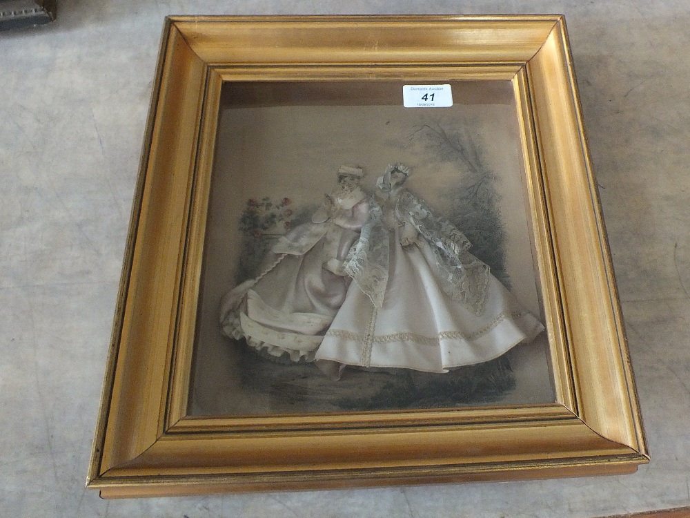 A framed three dimensional display of two Victorian ladies in silk and lace dresses,