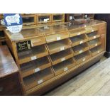 A Oak glazed shop counter with sixteen sliding drawers (part of the shop fittings from Nurseys of