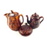 Two 19th Century treacle glazed teapots with relief figure decoration and a flask