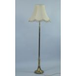 An Edwardian brass standard lamp, plain column, semi fluted at the bottom, on an outswept base and