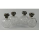 A set of four late Victorian cut glass and silver mounted scent bottles, the tops each embossed with