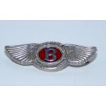 A silver Bentley pin badge, in the form of Bentley logo, with red enamel centre bearing letter B,