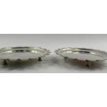 A matched pair of Edward VII/George V silver salvers, with shaped rims, each raised on three stud