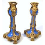 A pair of Sevres style gilt metal and blue porcelain candlesticks, each of rococo design with