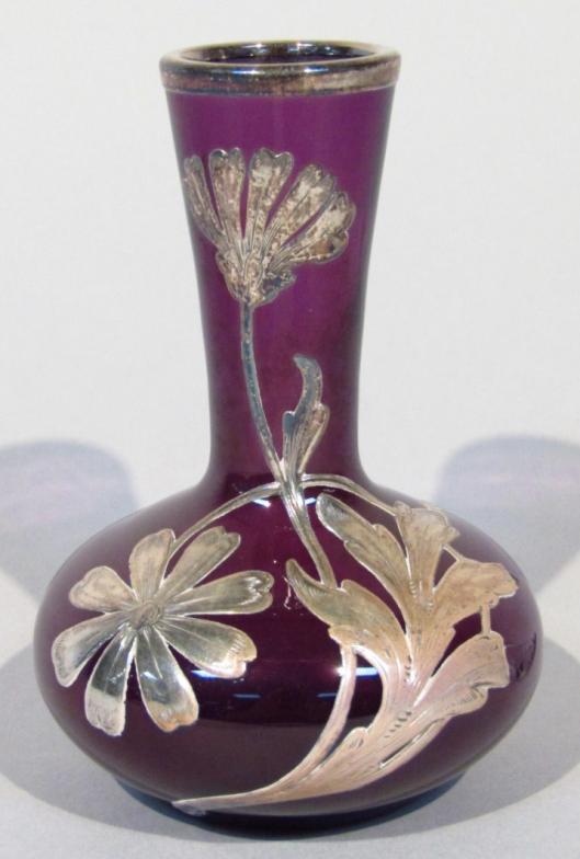 A late 19thC amethyst and overlay glass vase, raised with white metal flowers and leaves, with an