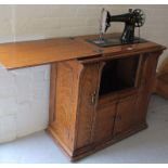 An early 20thC Singer sewing machine, on an articulated oak cabinet base, with hinged lid above