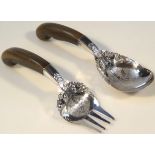 A pair of salad servers, each with heavily etched and pierced ends, decorated with scrolls,