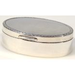 An Edwardian silver patch box, the oval lid with a bell flower border, hinging to reveal a gilt