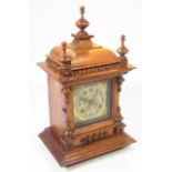 An Edwardian walnut cased mantel clock, the domed top with triple finials above a 13cm back plate