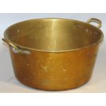 An early 20thC brass stew pot, the circular body flanked by 'C' shaped carrying handles, 56cm wide.