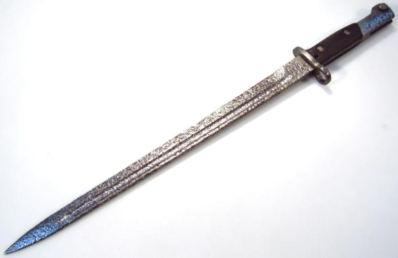 A 20thC bayonet, with unusual textured blade, part wooden grip and pierced guard, 53cm wide. (AF)
