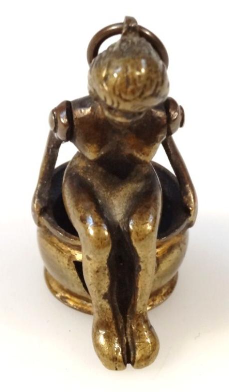 An early 20thC cast metal novelty cigar cutter, formed as a nude lady in seated position on an