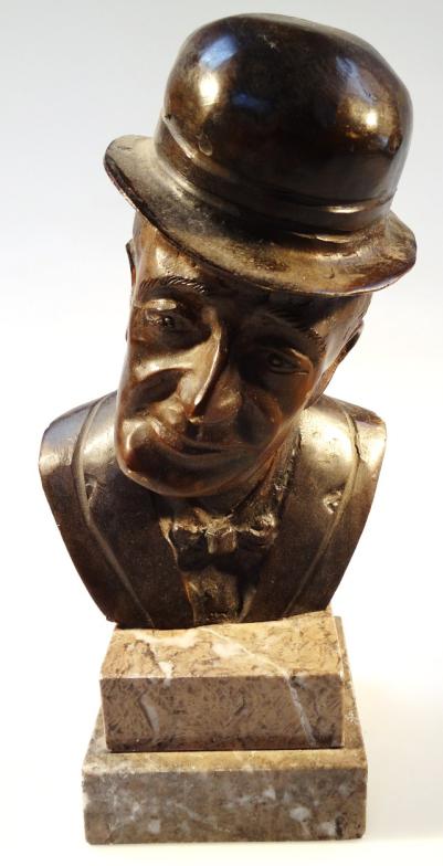 A 20thC bronze and marble finish bust, of a gentleman quarter profile in top hat and bow tie on a