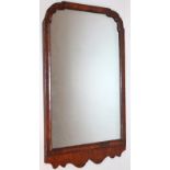 A 19thC walnut mirror, the shaped part cushioned frame with a carved apron holding a plain glass,