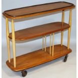 An Ercol style lightwood three tier trolley, with oblong sections held by shaped pieces on