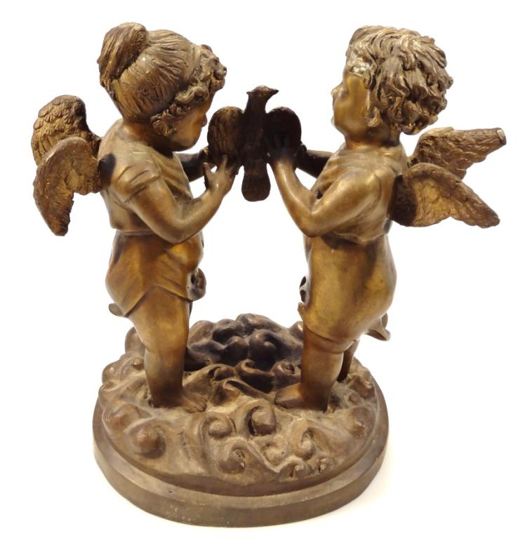 A 20thC bronzed classical figure group, of two cherubs standing holding a bird on a naturalistic