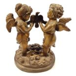 A 20thC bronzed classical figure group, of two cherubs standing holding a bird on a naturalistic