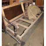 An early 19thC mahogany framed bench settle, the shaped rounded back raised above scroll supports on