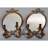 A pair of girandole wall mirrors, each of oval outline broken by crosses and surmounted by hook