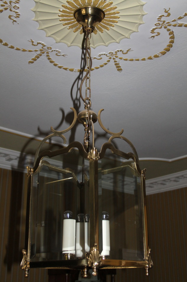 A brass lantern shaped light fitting, with four bevelled glass sides, chain suspension, the