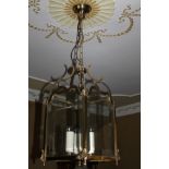 A brass lantern shaped light fitting, with four bevelled glass sides, chain suspension, the