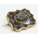 A Victorian memorial brooch, black enamel, gold colour lettering to the front with carved jet