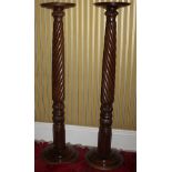 A pair of mahogany torcheres, the circular dished top on a wrythen and leaf carved column and