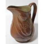 A 19thC brown stoneware jug, the moulded body raised with tulips, with a shaped handle, on