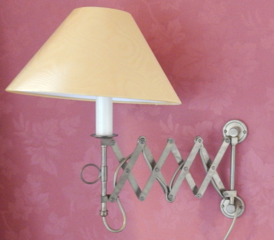 A pair of brass adjustable wall lights, each with a simulated candle fitting, extending to