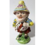 An early 19thC porcelain Mansion House dwarf, typically decorated in standing pose with gilt orb